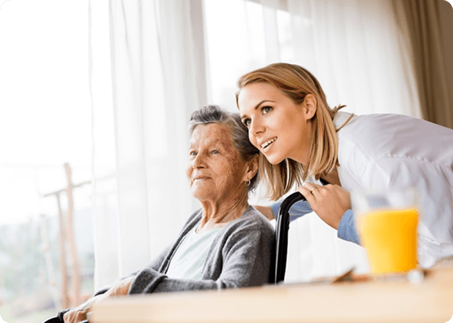 A carer supporting a resident in a bright care home setting